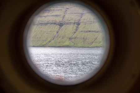 Landscape of the faroe island as seen through a ships portholeの写真素材