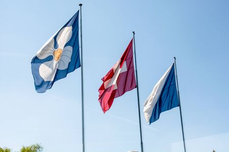Flags of Zurich and Switzerland on flag poles on a summer day in Zurich with blue skyの写真素材