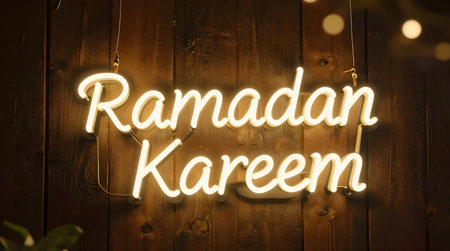 A neon sign reading Ramadan Kareem hangs on a wooden wall with warm glowing lights and bokeh in the backgroundの素材