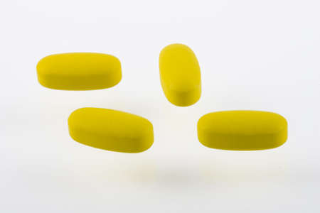 Yellow pills on white backgroundの写真素材