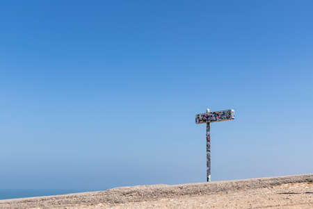 Nazare, Portugal - July 18, 2019: A roasdsign covered with stickers close to the Nazare Lighthouseのeditorial素材
