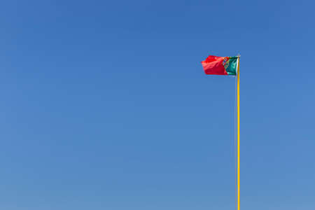 Portuguese flag photographed against a blue skyの写真素材