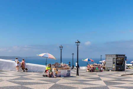 Nazare, Portugal - June 28, 2021: Woman in traditional clothing selling dried fruits on the Miradouro do Subercoのeditorial素材