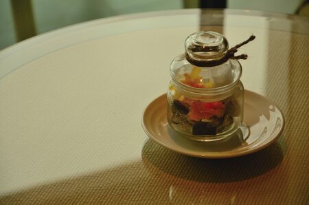 Photo of a glass jar with candy inside it on ceramic plate の写真素材