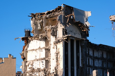 Demolished destructed building ruins. Demolition site in european city. Ruined house on a bright blue sky on a sunny day.の写真素材