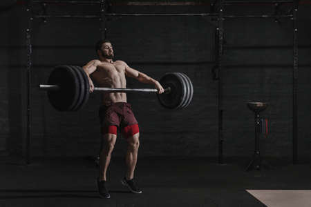 Muscular man lifting a barbell in crossfit gym.の写真素材
