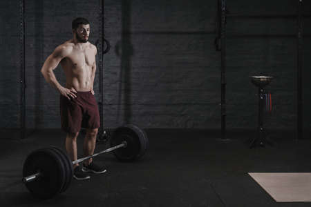 Young cross fit athlete resting after lifting weight at the gym. Handsome man doing functional training. Practicing powerlifting. Workout exercisesの写真素材