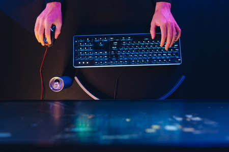 Pro gamers hands on professional gaming keyboard and computer mouse in neon colourの写真素材