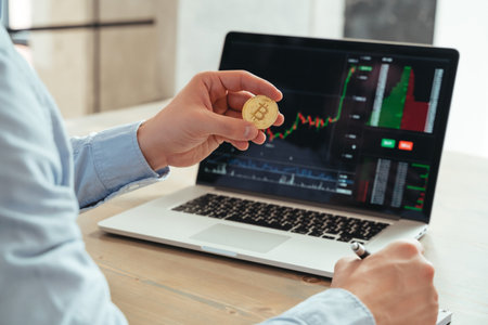 Cropped shot of trader investor holding bitcoin, using laptop, investing in cryptocurrencyの写真素材