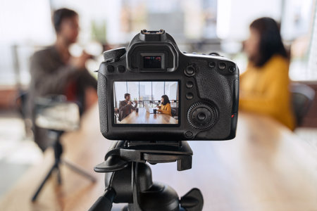 Man and woman recording video podcast on camera in studioの写真素材