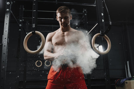 Muscular crossfit athlete clapping hands and preparing for workout at the gym