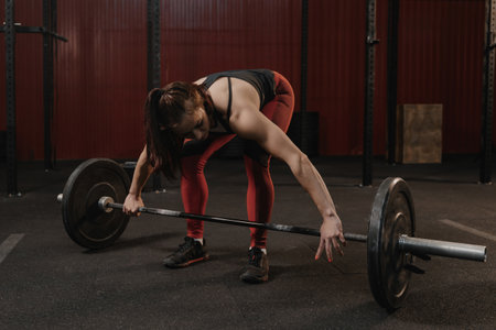 Young crossfit woman preparing barbell for lifting weight at the gym.の写真素材