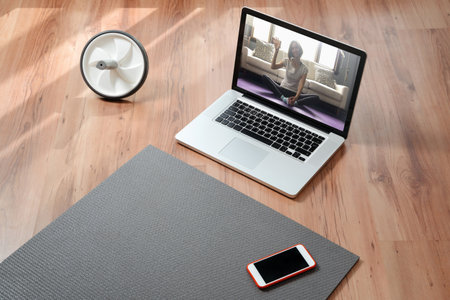 Yoga teacher online. Closeup of equipment for online fitness at home: exercise mat, smartphone,...