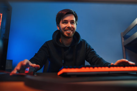Portrait of young pro gamer having fun, playing online video games at home at night, streaming play...