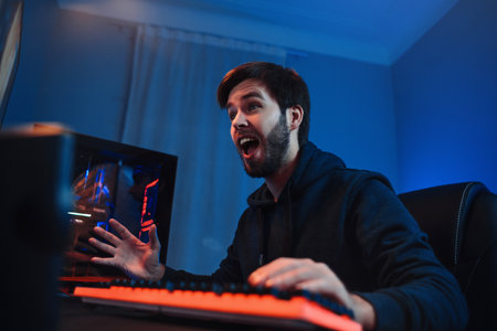 Portrait of professional male gamer playing tournaments online games at home, happy with winning the...