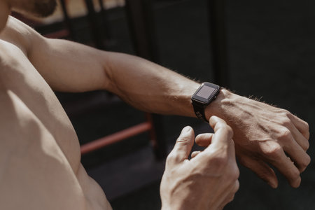 Shirtless athlete using smartwatch while resting workout. Fitness gadgets concept. Space for text....