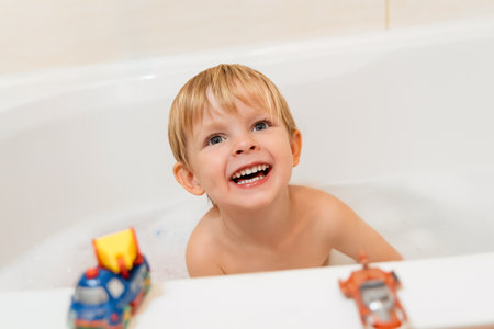 Portrait of a happy little boy in the bath. Smiling child playing with toys while bathing in the bathtubの写真素材
