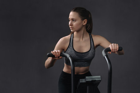 Attractive young woman in sportswear using exercise bike for cardio workout at fitness gym. Fit...