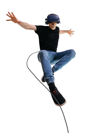 Young man imagines himself a superhero while using VR glasses for playing computer game. Male portrait on white background.の写真素材