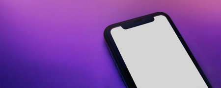 Close up of smartphone with white screen on pink purple neon surface. Copy space for app, product, or user interface presentation. Wide horizontal banner of phone mock up with blank screenの写真素材