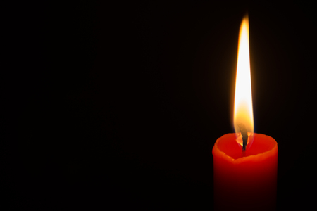One red  lit candle isolated on a black background.の写真素材