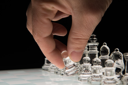 Hand holding the  pawn to make the first moveの写真素材