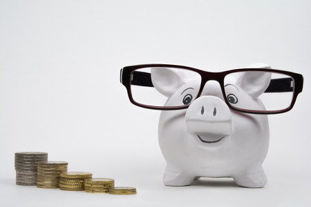 Coins lined up from short to tall stacks beside of a piggy bank with glassesの写真素材