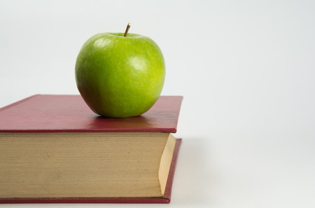 Green apple on an old red hardcover bookの写真素材