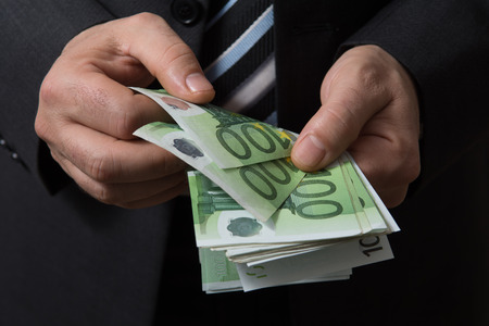 Man in black suit counts euro moneyの写真素材