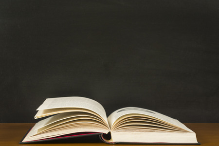 Open book in front of a blackboardの写真素材