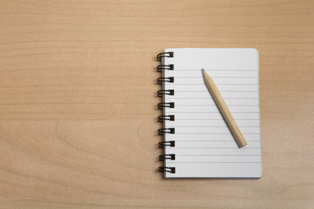 notepad with pencil on a wooden tableの写真素材