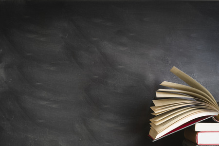 an open book front of a blank black boardの写真素材