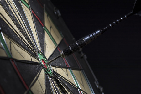 Dart in bulls eye of dartboard, close upの写真素材