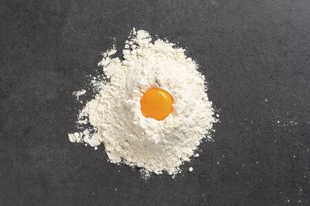 Pile of wheat flour and and egg yolk on a marble kitchenの写真素材