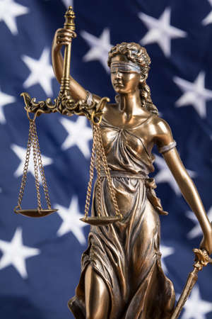 The statue of justice Themis or Justitia, the blindfolded goddess of justice against the flag of the United States of America, as a legal conceptの写真素材