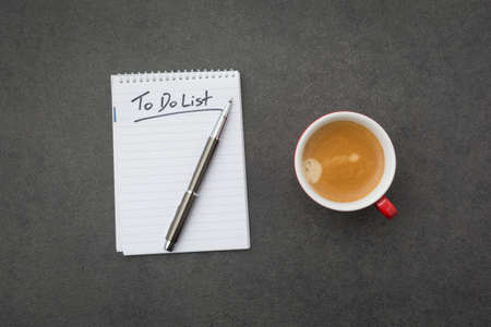 Notepad with the to do list and red coffee cup on grey desk. High angle viewの写真素材