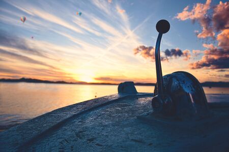 Beautiful shot of a sunset focused on an old boat's throttle with a dreamy sunsetの写真素材