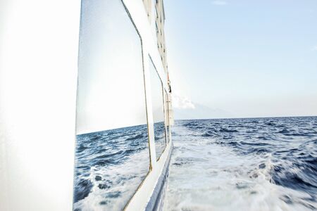 Snapshot of a vessel cruising the water and sea reflection on the windowの写真素材