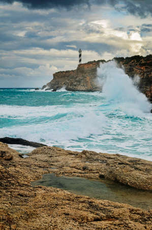 waves crashing on the rocks at the foot of the lighthouseの写真素材