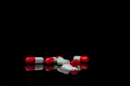 Medicine capsules thrown away with black backgroundの写真素材