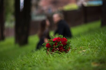 A wonderful bouquet of roses lying on the bright green grass on the background of the newlywedsの写真素材