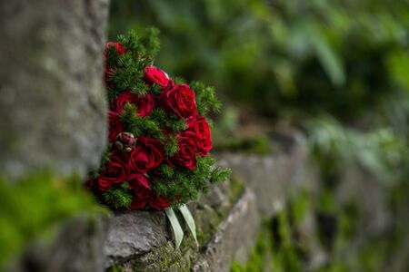 Bouquet of red roses lying on the old stones covered with mossの写真素材
