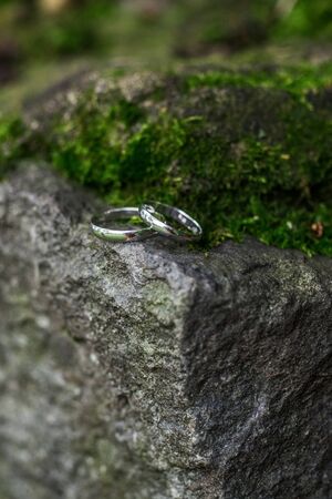 Platinum wedding rings on the edge of a cliff in the mossの写真素材