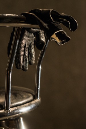 Black leather gloves hanging on the back metal bar stoolの写真素材