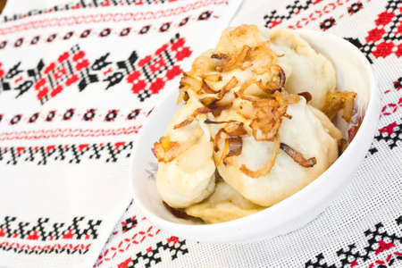 Ukrainian dishes - dumplings with fried onion on traditional embroidered towelの写真素材