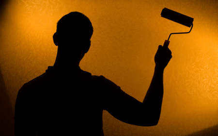 Renovation - Back lit silhouette of man and paint-rollerの写真素材