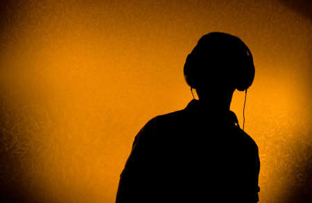Silhouette of male DJ with earphones (back light)の写真素材