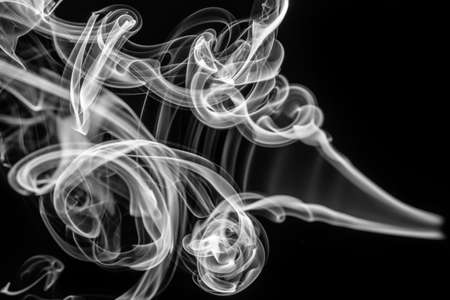 Abstract pattern: white smoke swirls and curves on black の写真素材