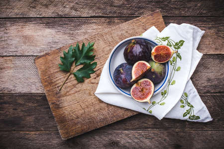 Figs in flat dish on choppingboard and napkin in rustic style. Autumn season food photoの写真素材
