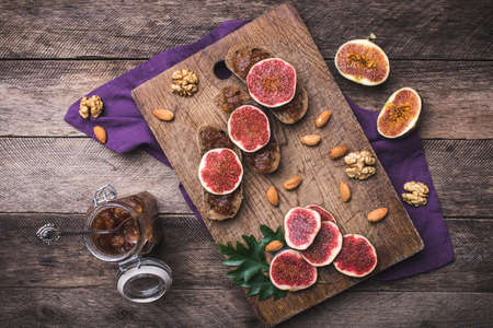 Sliced figs, nuts and bread with jam on choppingboard in rustic style. Autumn season food photoの写真素材